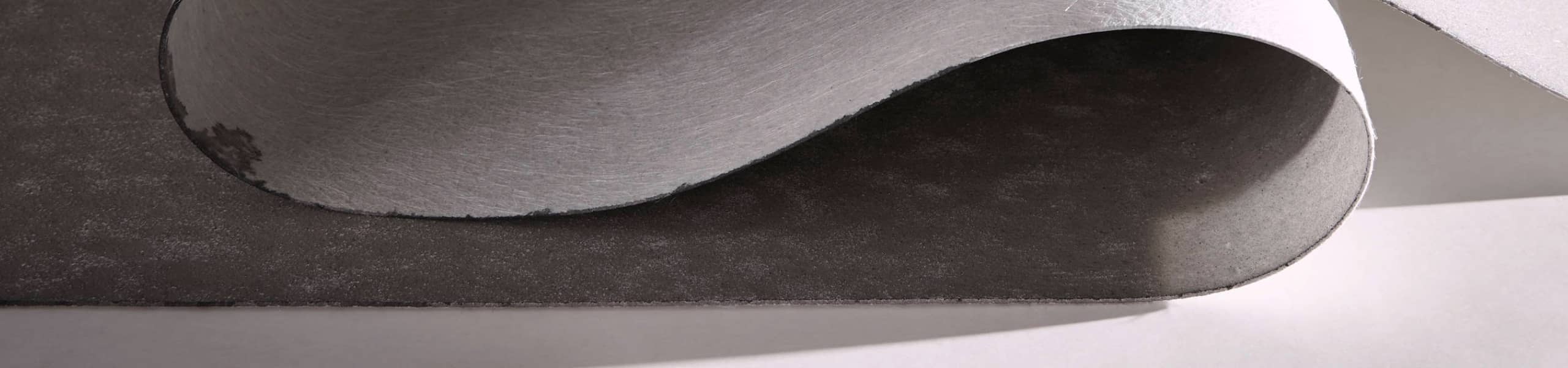 Zoom sur un lé de sol souple de couleur grise en train d'être déroulé.