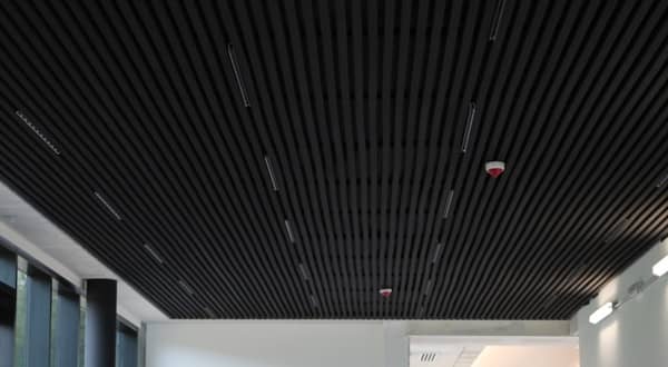 Vue d'ensemble d'une salle de conférence avec plafond acoustique en lames noires avec lumières LED incrustées.