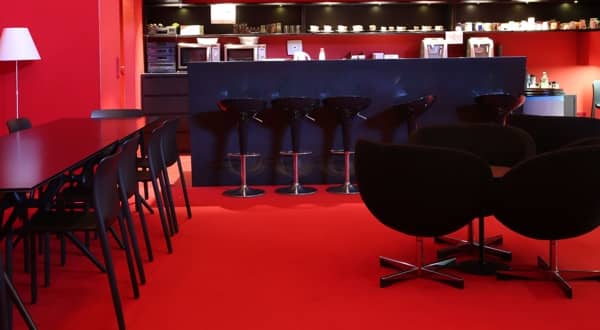 Bar loung d'entreprise, moquette velours rouge, mur, plafond rouge, mobilier noir : comptoir, tabouret, fauteuils, table, chaises.