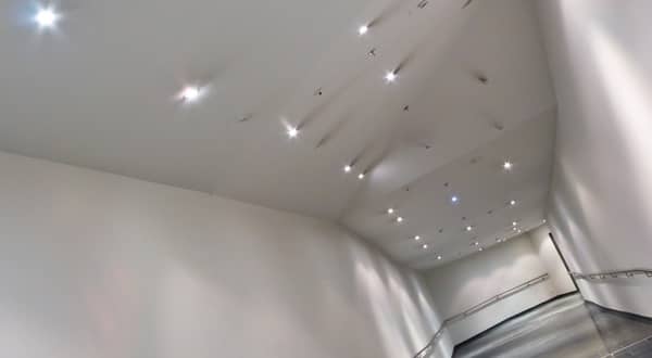 Vue d'ensemble d'un couloir profond avec plafond en plaques de plâtre design et petits néons incrustés.