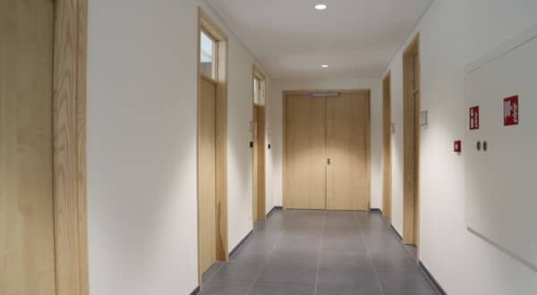 Vue d'ensemble d'un couloir d'entreprise avec six portes coupe-feu en bois dont une double porte dans le fond, cloison coupe-feu.